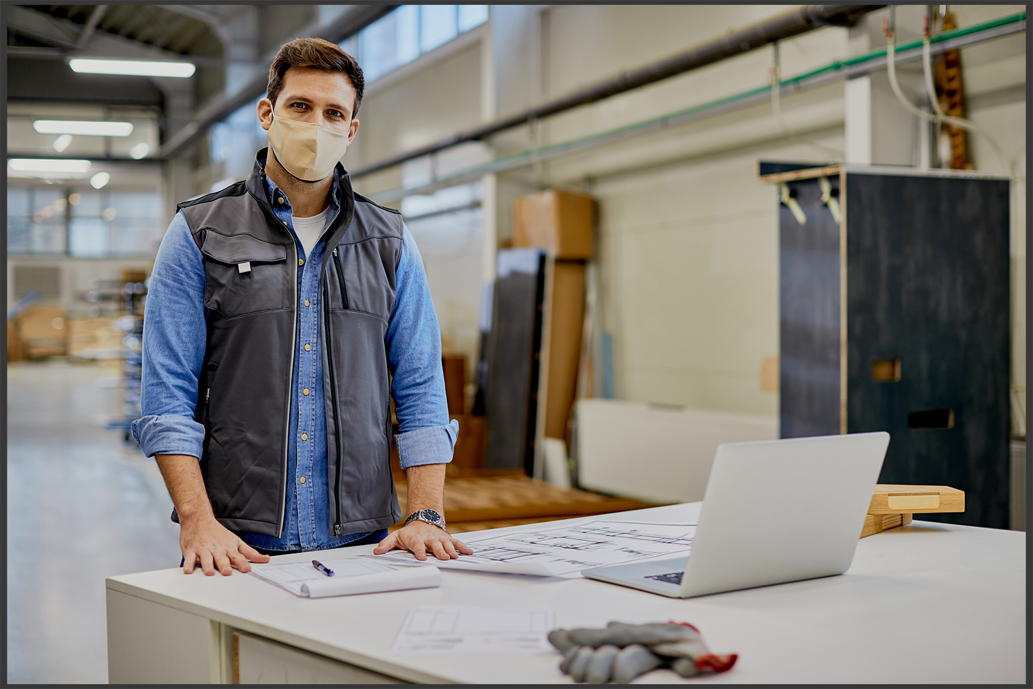 woodworking-engineer-with-face-mask-working-at-industrial-facility-and-looking-at-camera